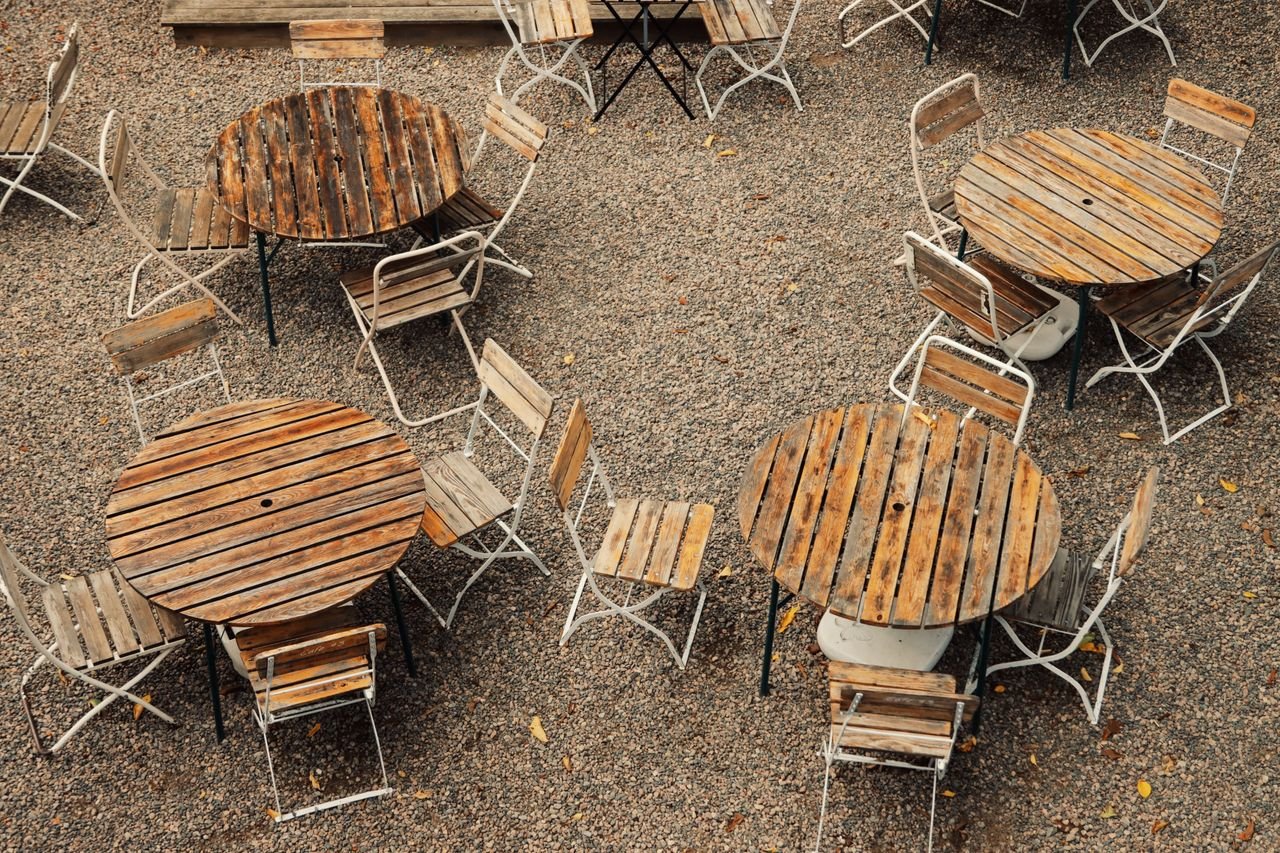 Rustic wooden tables and chairs on a gravel patio in Jönköping, Sweden.