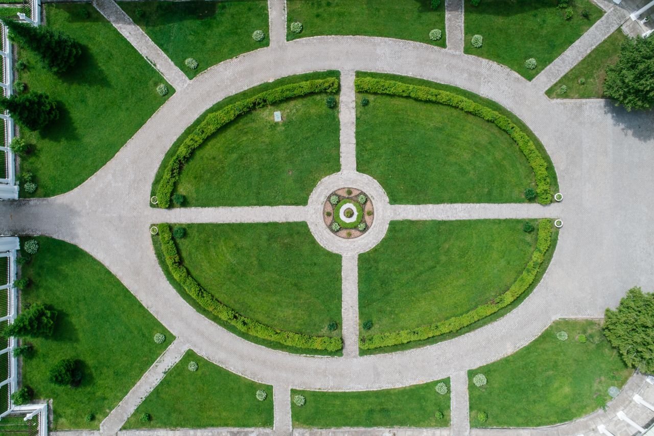Aerial shot showcasing symmetrical pathways and lush greenery in a park setting.